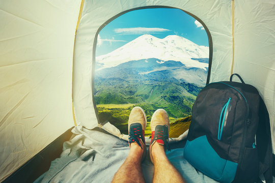Hiker Man Sitting In A Tourist Tent by The Elbrus Mount Travel Discovery Concept. View Of Legs. Point Of View Shot