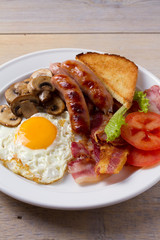 Full English or Irish breakfast: sausages, bacon, egg, mushrooms, tomatoes and toasts. Nutritious morning meal