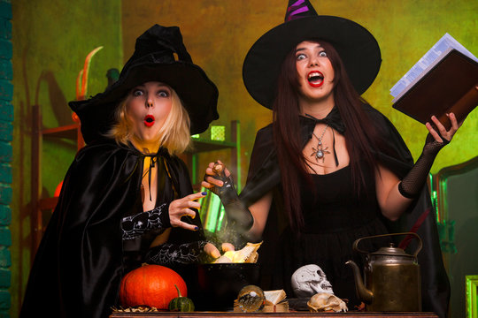 Photo of two witches with book of incantations in dark room