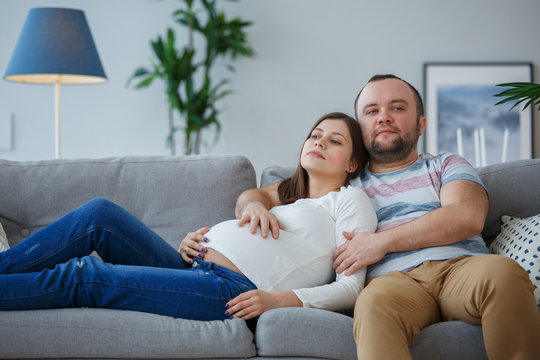Image of pregnant woman and man on gray sofa