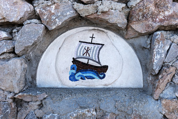 Fototapeta na wymiar Closeup blue sailing ship mosaic tiles on an old stone wall