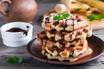 Homemade Belgian waffles with chocolate sauce and banana slice on a plate