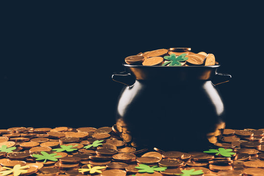 black pot with golden coins and shamrock isolated on black, st patricks day concept