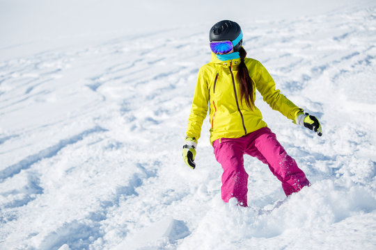 Picture of athlete girl in helmet and mask, snowboarding from snowy mountain slope