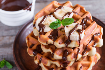 Homemade Belgian waffles with chocolate sauce and banana slice on a plate