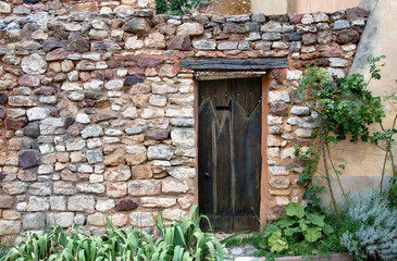 Fototapeta na wymiar Roussillon (Vaucluse) Mur en vieilles pierres et porte en bois, Luberon, Provence, France