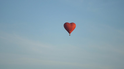 Obraz premium Hot air balloon shape of a heart in the blue sky. Aerostat, Airship. Red balloon.