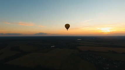 Aerial view Hot air balloon in the sky over a field in the countryside in the beautiful sky and sunset. Balloon silhouette with sunrise, Aerostat fly in the countryside.