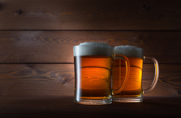 Two glasses of golden beer on wooden background