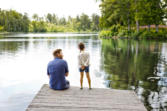 Father and daughter on pier beside lake in Friseboda, Sweden