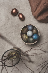 Top view of easter eggs and willow branches in vase on concrete surface