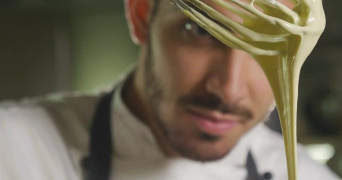 A professional confectioner prepares a cream by beating fresh eggs bo in a basin to make a cake. Concept of: desserts, cakes, chefs, gourmet, cookery school.