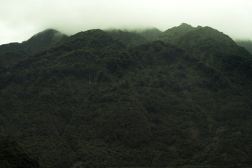 Paisaje de picos de monta&ntilde;as verdes con cielo blanco nublado