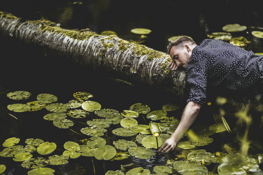 Man lying on log in Sodermanland, Sweden