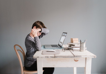 boy sitting at his desk with the computer being tired 