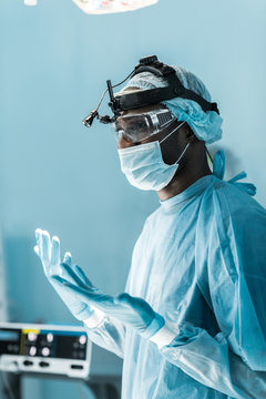 side view of african american surgeon in medical gloves in operating room
