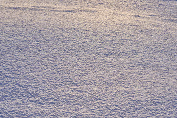Natural background - ice surface of snow illuminated by the rays of the evening sun. The sun's rays bouncing off the gleaming crystals loose ice..
