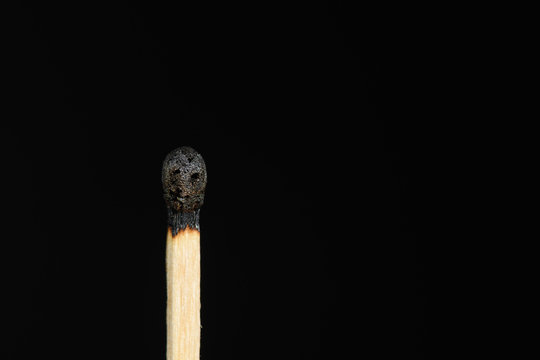 Match with the burned head showing a smiley on a black background closeup