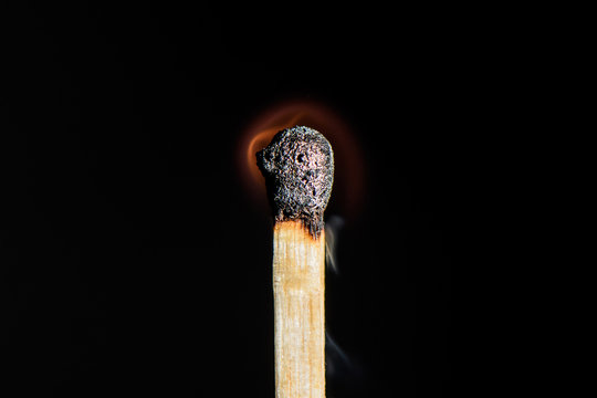 The match is almost completely extinguished on black background closeup