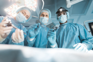 bottom view of multicultural surgeons looking at patient during surgery