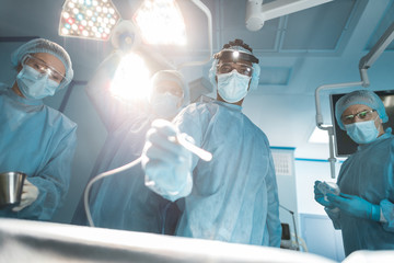 bottom view of multicultural surgeons looking at camera during surgery