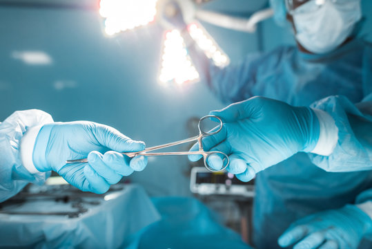 cropped image of nurse passing medical scissors to surgeon