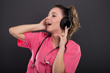 Beautiful young doctor singing listening to headphones