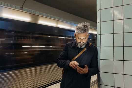 Man texting at train station in Stockholm, Sweden