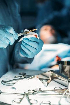 cropped image of surgeon cleaning scalpel from blood in surgery room