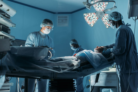 multicultural doctors preparing patient for surgery in operating room
