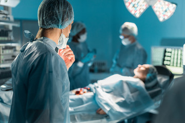 multicultural surgeons and female patient in operating room