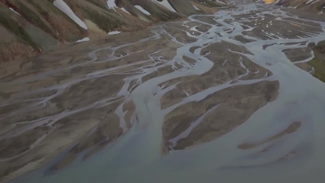 Tilt up from river delta to Icelandic snowy mountains