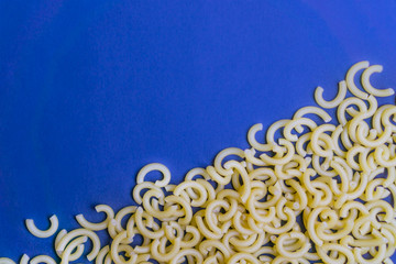Raw noodles on blue background, copy space