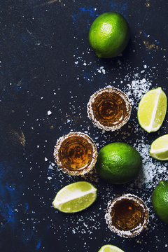 Strong alcoholic drink with salt and lime, dark background, top view