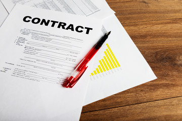 Pen and contract papers on wooden desk