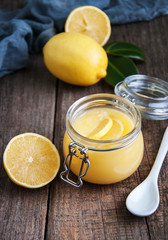 Lemon curd in glass jar with fresh lemons
