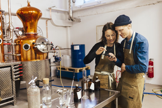 Young couple using smartphone at gin distillery