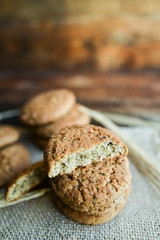 fresh homemade oatmeal cookies on wooden background with spikes of oats
