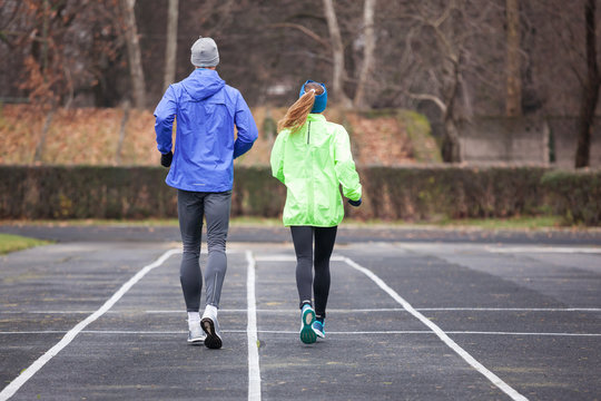 Full Lenght Shot From Behind Of A Young Couple Running.