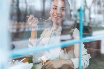Energy in food. Joyful pleasant gay woman smiling while eating during lunch and looking aside