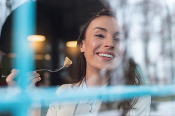 Inspired mood. Positive pretty calm woman grinning while holding fork and turning head