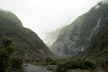 Naklejka na ściany i meble Paisaje de picos de montañas verdes con cielo nublado en Nueva Zelanda