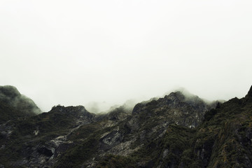 Fototapeta na wymiar Paisaje de picos de montañas verdes con cielo nublado en Nueva Zelanda