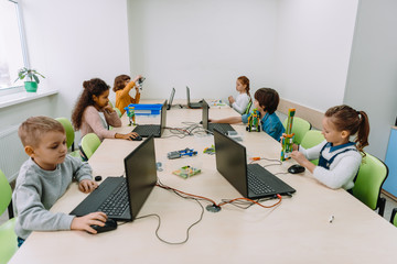 group of focused kids working with computers on machinery class