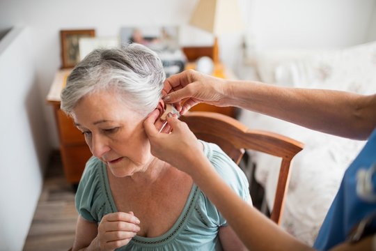 Nurse putting hearing aid to a senior woman