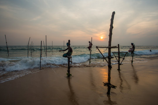  Silhouettes of the traditional Sri Lankan stilt fishermen on a stormy in Koggala, Sri Lanka. Stilt fishing is a method of fishing unique to the island country of Sri Lanka 

