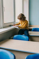 adorable little kid writing homework on windowsill