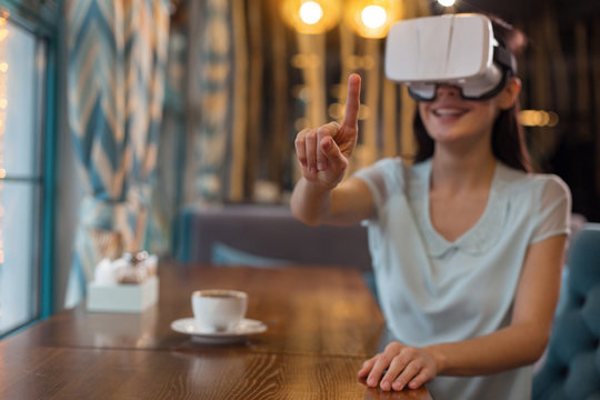 Let me touch. Selective focus of female hand pointing while nice appealing woman sitting at table while drinking coffee