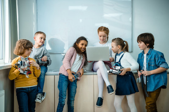 group of kids with laptop and robots on stem education class