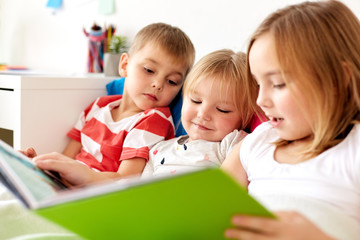little kids reading book in bed at home